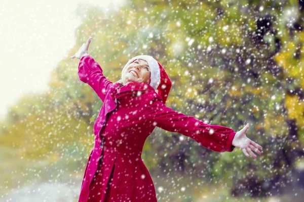 Жінка з Санта-капелюхом насолоджується першим снігом — стокове фото