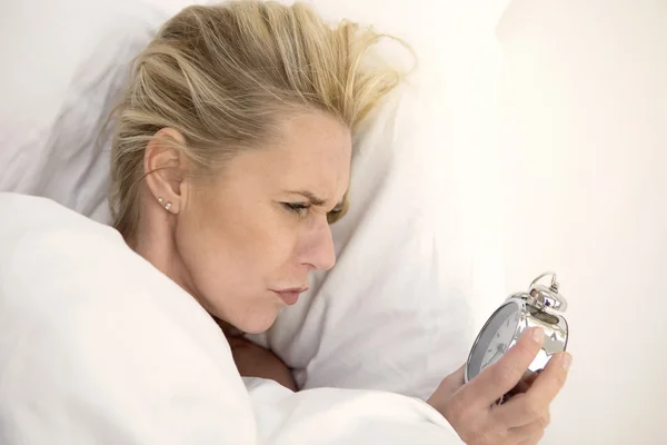 Kvinna i sängen tittar på hennes väckarklocka — Stockfoto
