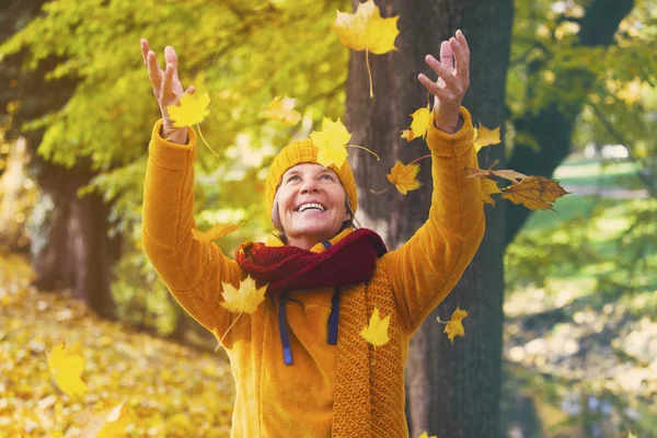 Femme dans le parc jetant des feuilles dans l'air — Photo