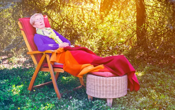 Femme plus âgée dormant dans la chaise dans le jardin — Photo