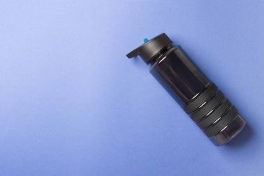 Siyah plastik spor şişesi mavi arkaplanın sağ tarafında fotokopi alanı ile duruyor.
