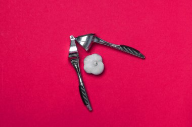 Sarımsak için metal pres ve kırmızı arka planda sarımsak..