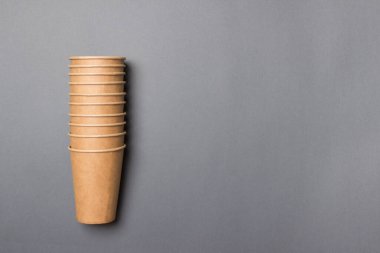 Çevre dostu karton bardaklar, fotokopi alanı olan gri bir arka planda yatıyor. Model-up. Yakın plan. Ekoloji kavramı.