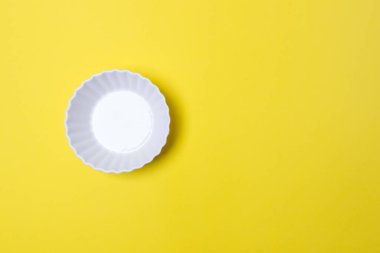 Kopyalama alanı olan sarı renkli kağıtta boş beyaz tabak.