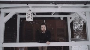 Ahşap sundurma üzerinde siyah kazak duran yakışıklı genç adam.