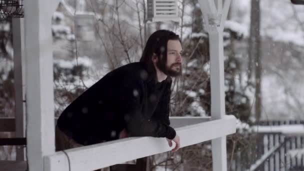 Knappe jongeman in zwarte trui staande op de houten veranda. — Stockvideo