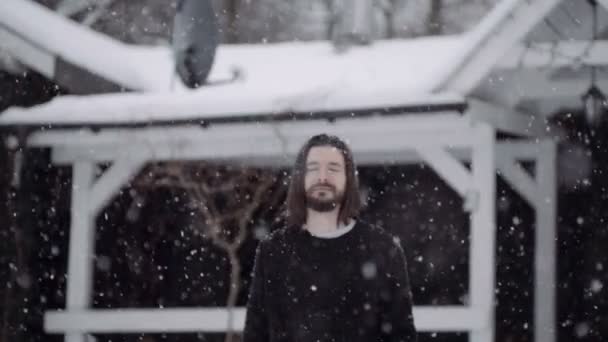 Bello giovane in maglione nero in piedi vicino a una vecchia casa di legno . — Video Stock