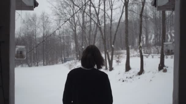 Bello giovane uomo in maglione nero in piedi dietro vicino alla vecchia casa di legno . — Video Stock