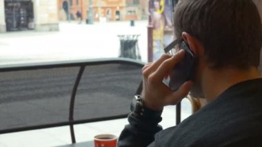 Kafede otururken telefonda konuşan adam.