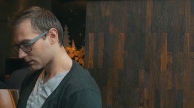 Restoranda oturan ve bir kameraya gülümseyen şık genç adam.