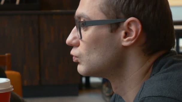 Pensive man wearing glasses drinking coffee. — Stock Video