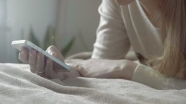 Evde yatakta yatarken ve smartphone kullanarak genç kız.