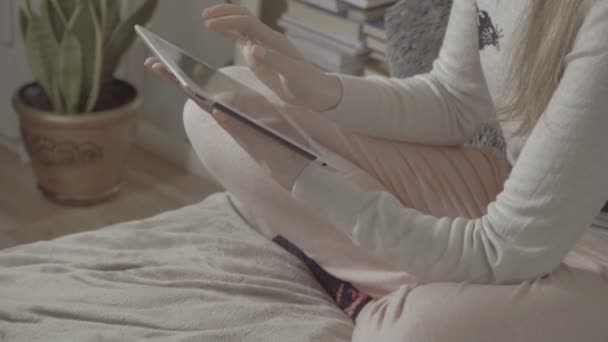 Junges Mädchen sitzt zu Hause mit Tablet im Bett. — Stockvideo