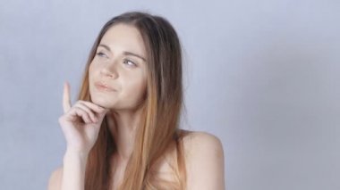 Gri arka plan üzerinde izole güzel dalgın genç bir kadın portresi.