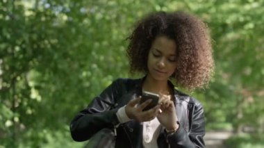 Cep telefonu, açık kullanarak siyah kıvırcık saçlı güzel genç kız.