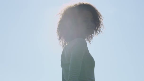Unga afro amerikansk kvinna avkopplande i parken med en solnedgång bakom henne. — Stockvideo