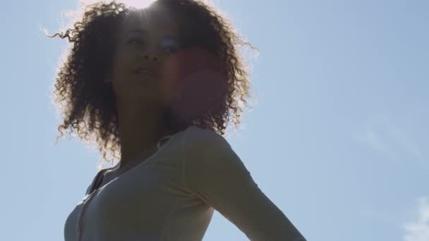 Jeune femme afro-américaine se détendre dans le parc avec un coucher de soleil derrière elle . — Video