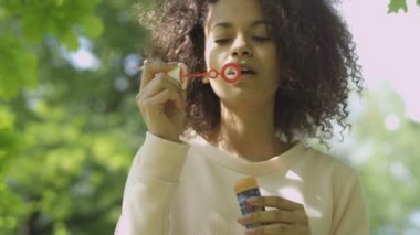 Sabun köpüğü, açık üfleme genç güzel afro saçlı kadın.