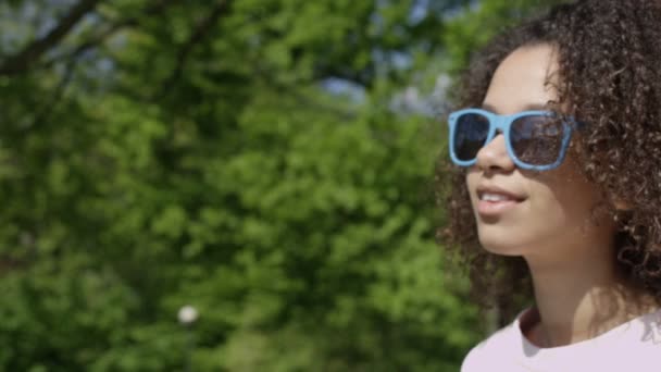Närbild porträtt av en vacker blandad ras kvinna i solglasögon, utomhus. — Stockvideo