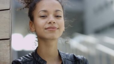 Güzel gülümseyen Afrikalı kadın kentsel arka planda bir kamera için arıyorsunuz. 