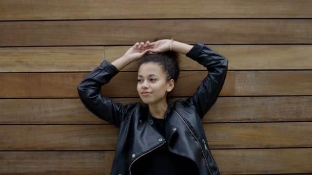 Joven mujer afroamericana posando al aire libre sobre fondo de madera . — Vídeos de Stock