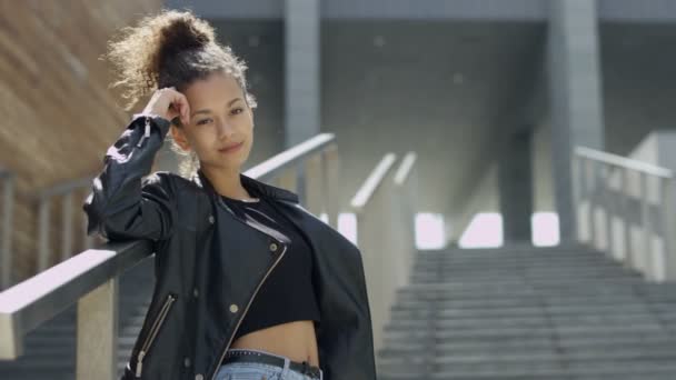 Hermosa mujer africana sonriente en el fondo urbano mirando a una cámara . — Vídeo de stock