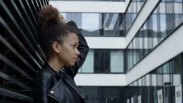 Hermosa mujer africana sonriente en el fondo urbano mirando a una cámara . — Vídeo de stock