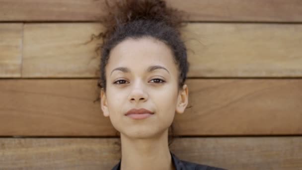 Jonge african american vrouw poseren buitenshuis op houten achtergrond. — Stockvideo