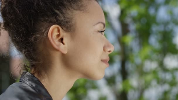 Joven hermosa mujer de raza mixta sonriendo felizmente en un parque verde . — Vídeo de stock