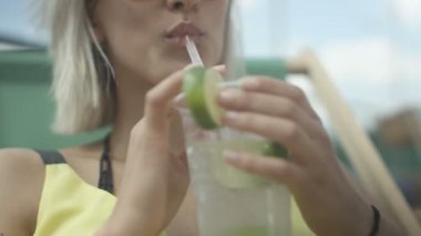 Onun yaz tatile kamışla taze meyve süslenmiş bir tropikal mojito kokteyl içme bir kadının yakın çekim.