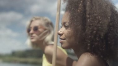 Güzel genç yarış kızlar karışık göl kenarında konuşmak ve iyi vakit geçiriyor. 