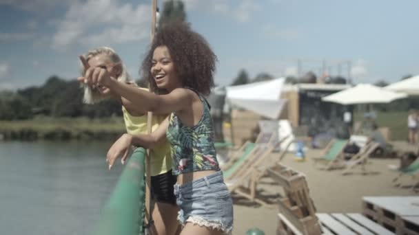 Δύο όμορφα νεαρά κορίτσια απολαμβάνουν το καλοκαίρι κοντά στη λίμνη. — Αρχείο Βίντεο