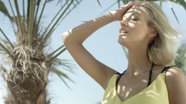 Tropik sahilde poz seksi sarışın kız.