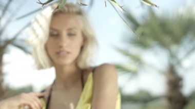 Tropik sahilde poz seksi sarışın kız.