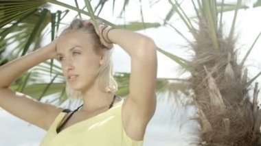 Tropik sahilde poz seksi sarışın kız.