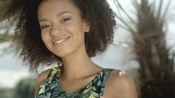 Tropik sahilde bir kameraya gülümseyen güzel genç Afro Amerikan kız portresi. — Stok video