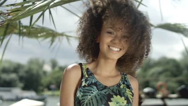 Retrato de una hermosa adolescente afroamericana en la playa tropical sonriendo a una cámara . — Vídeos de Stock