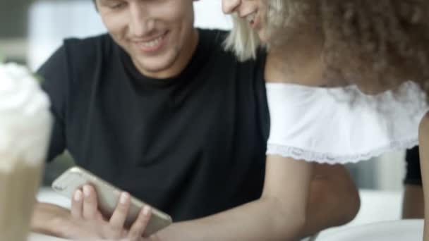 Des gens de race mixte assis à une table dans un restaurant utilisant un téléphone portable .