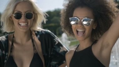 İki genç mutlu hippi kız eğleniyor, açık güneş gözlüğü.