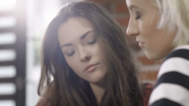Närbild på två vackra unga tjejer som studerar på moderna loft apartment. — Stockvideo