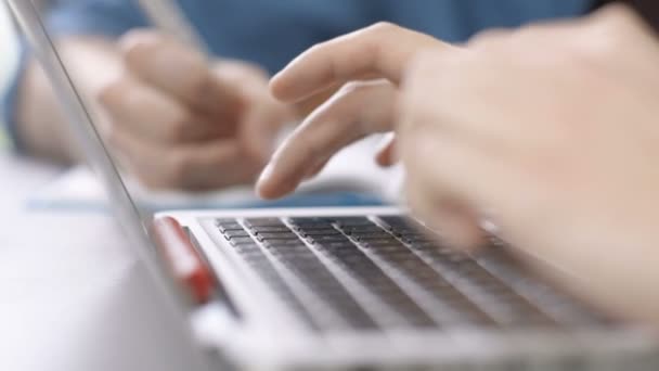 Close-up de jovens usando laptop e escrever algo em notebook em sala de aula / escritório . — Vídeo de Stock