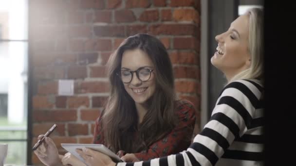 Två vackra unga tjejer som studerar på moderna loft apartment. — Stockvideo