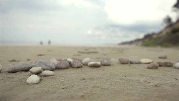 Paysage de plage de sable avec des pierres et des gens qui marchent sur un fond . — Video