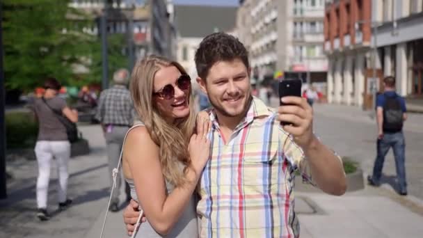 Attractive couple taking self-portrait with smartphone in a city street — Stock Video