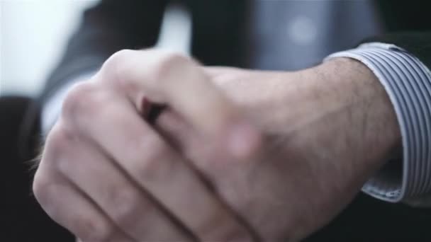 Nahaufnahme der Hände eines kaukasischen Mannes, der in einem hellen Raum sitzt — Stockvideo