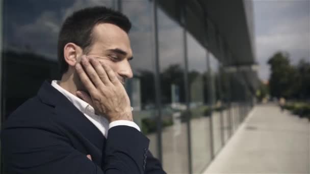 Bonito homem de negócios preocupado esperando por alguém ao ar livre no prédio de escritórios . — Vídeo de Stock