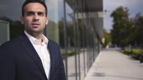 Handsome concerned businessman waiting for someone outdoors the office building. — Stock Video