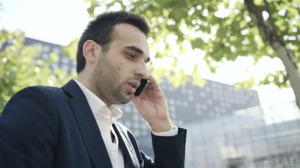 Joven hombre de negocios guapo hablando por teléfono móvil en la ciudad — Vídeo de stock