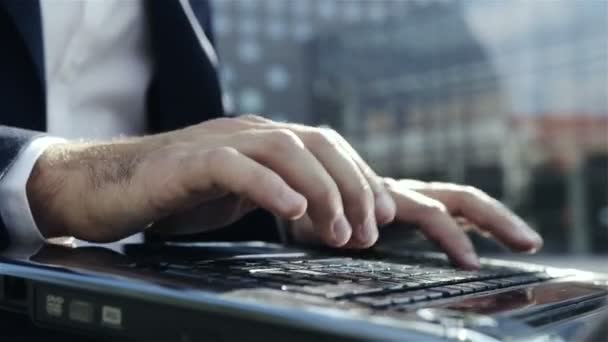 Person som arbetar på laptop på park nära kontor. närbild av fingrar att skriva på tangentbordet. — Stockvideo