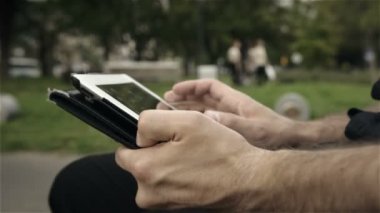 işadamı bir dokunmatik ekran cihaz tutan bir parkta.